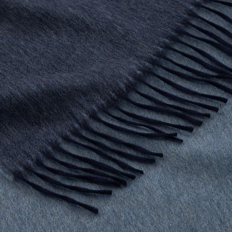 Navy blue scarf with fringe detail on a matching fabric background