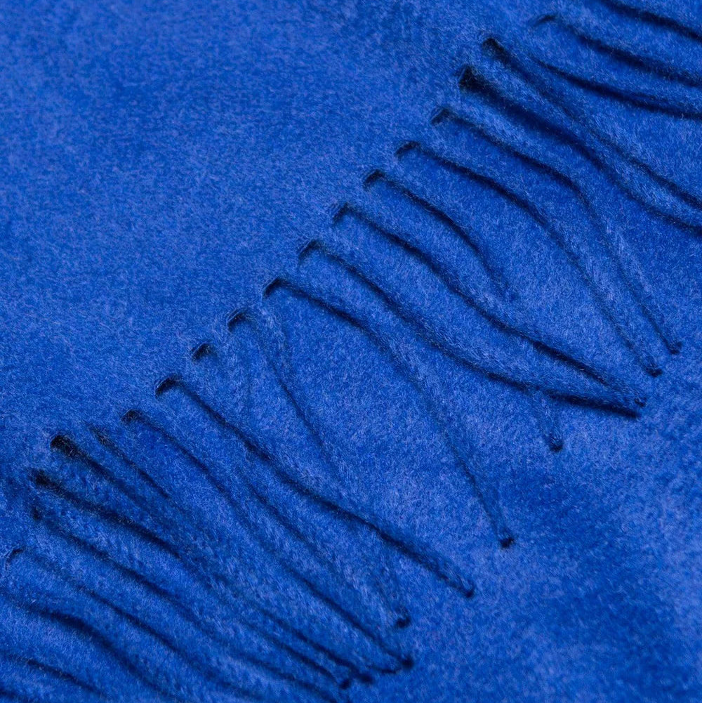 Close-up of a blue fabric with fringes on a matching blue background